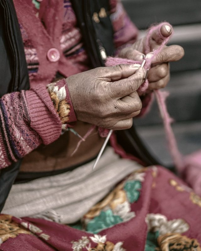 Hands working yarn with needles