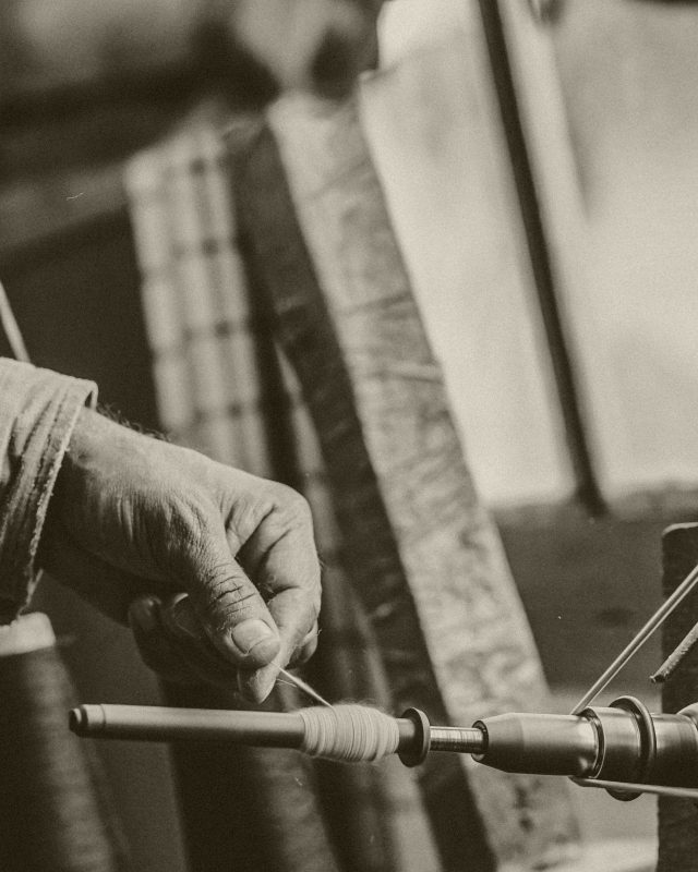 A hand setting a spindle against loom machinery