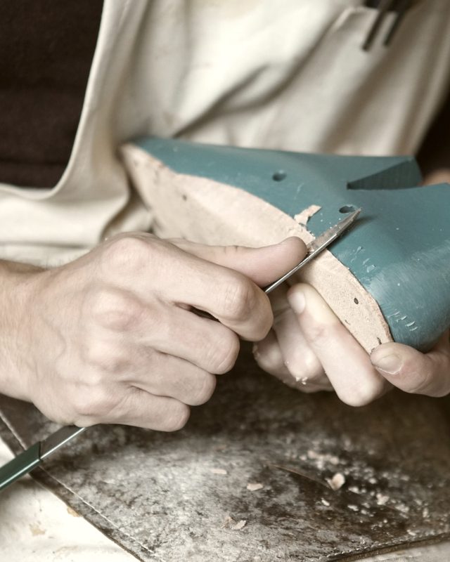 Hands in a work apron finishing a piece at the bench